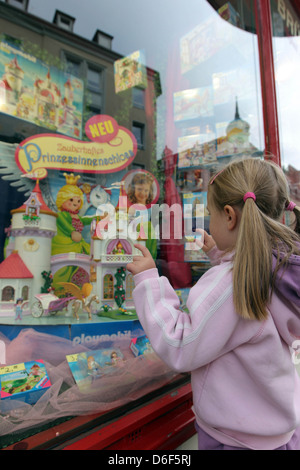 Flensburg, Deutschland, Mädchen steht vor einem geschmückten Fenster und blickt auf das Spielzeug Stockfoto