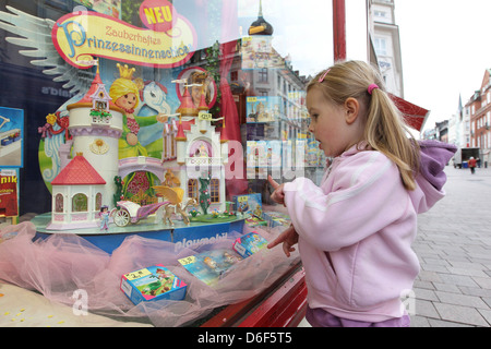 Flensburg, Deutschland, Mädchen steht vor einem geschmückten Fenster und blickt auf das Spielzeug Stockfoto