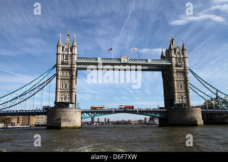 Turm-Brücke auf dem Fluss mit zwei London-Tour-Busse Kreuze und fliegen den Union Jack und die Flagge von St. George entnommen. Stockfoto