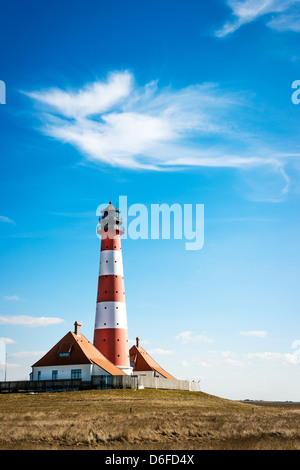 Vertikales Bild der Leuchtturm Westerhever an einem sonnigen Tag mit blauem Himmel und weißen Wolken. Stockfoto