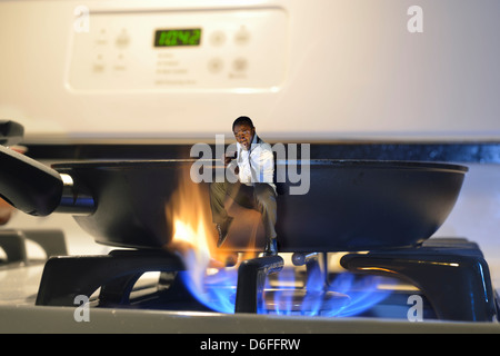 Mann springt aus der Pfanne und in das Feuer auf einem Herd Stockfoto