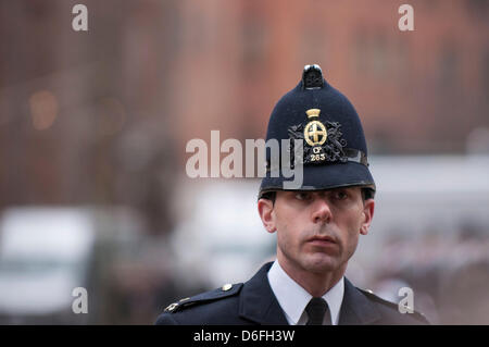 London, UK, 17. April 2013.  Trauerfeier von Baroness Thatcher findet in der St. Pauls Cathedral.  Wie Tausende von Menschen Linie erfolgt die Straßen ihre Aufwartung, Mitglieder von der Polizei Gesicht in Richtung der Massen zur Aufrechterhaltung der Sicherheit, als der Sarg in die Anschluß-Markierungsfahne, drapiert auf einer Lafette mit vollen militärischen Ehren. Stockfoto