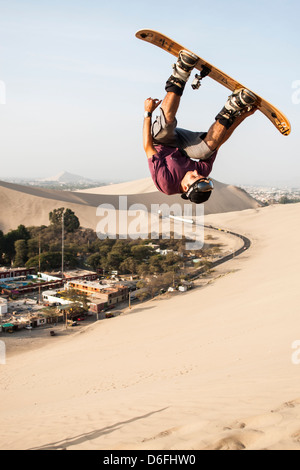 Junger Mann Sandboarding in Huacachina Oase. Stockfoto