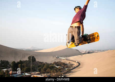 Junger Mann Sandboarding in Huacachina Oase. Stockfoto