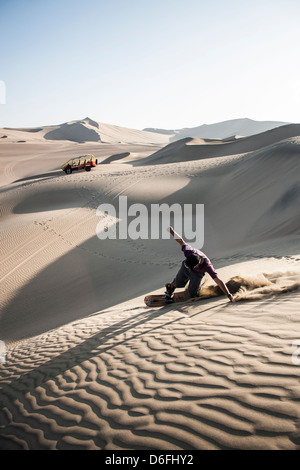 Junger Mann Sandboarding in der Wüste, die Oase Huacachina, im südwestlichen Peru umgibt. Stockfoto