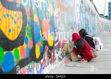 Asiatische Touristen schreiben an die Berliner Mauer in der Eastside Gallery Stockfoto