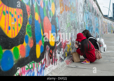 Asiatische Touristen schreiben an die Berliner Mauer in der Eastside Gallery Stockfoto