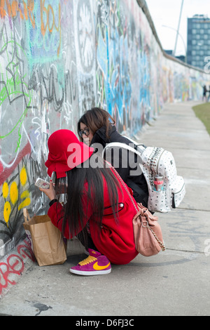 Asiatische Touristen schreiben an die Berliner Mauer in der Eastside Gallery Stockfoto