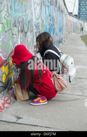 Asiatische Touristen schreiben an die Berliner Mauer in der Eastside Gallery Stockfoto