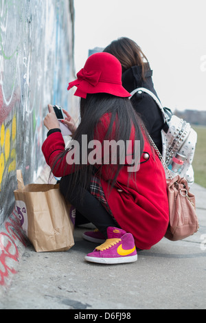 Asiatische Touristen schreiben an die Berliner Mauer in der Eastside Gallery Stockfoto