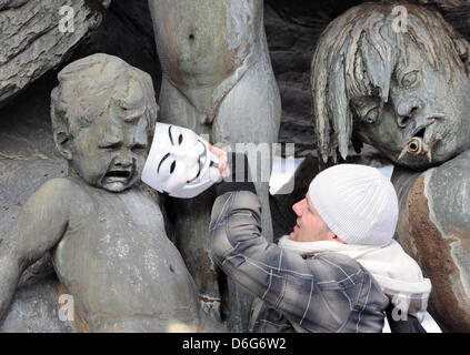 Ein Demonstrant setzt eine Maske auf eine Figur von der Neptun-Brunnen während einer Demonstration in Berlin, Deutschland, 11. Februar 2012. Der Protest ist gegen das Anti-Counterfeiting Trade Agreement (Acta). ACTA ist gedacht zur Durchsetzung der Rechte am geistigen Eigentum online. Nach Polizeiberichten protestierten etwa 2.000 Menschen in der Nähe von Rathaus in Berlin. Foto: SOEREN STACHE Stockfoto