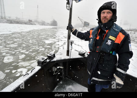 Ein Besatzungsmitglied des Eisbrechers beobachtet 'von Pechmann' Eisschollen auf dem Main am Hafen Aschaffenburg, Deutschland, 13. Februar 2012. Das Mainufer ist in einer dicken Schicht Schnee bedeckt und Situation versuchen, eine Wasserstraße für Binnenschiffe zu erstellen. Foto: Boris Roessler Stockfoto