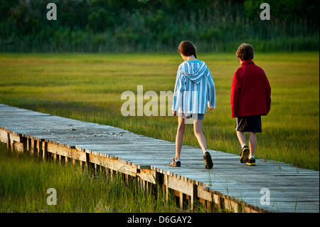 Kinder gehen auf eine Promenade weg durch die Salzwiesen. Stockfoto