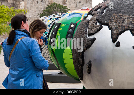 Jerusalem, Israel. 18. April 2013.  Touristen und einheimische untersuchen eine Ausstellung von achtzehn Cool Globes, jeder mit einem Gewicht von einer Tonne auf dem Display an der Alrov Mamilla Esplanade am Jaffa-Tor, mit dem Ziel, das Bewusstsein zu Klimawandel und Aufruf zum Handeln. Jerusalem, Israel. 18. April 2013.  Coole Kugeln: Heiße Ideen für ein Kühler Planet ist eine öffentliche Kunstausstellung Lösungen zum Klimawandel sensibilisieren soll. Cool Globes initiiert in 2005 und 2006 als eine gemeinnützige Organisation gegründet wurde. Coole 2007.Credit in Chicago uraufgeführt Globen: Nir Alon/Alamy Live News Stockfoto