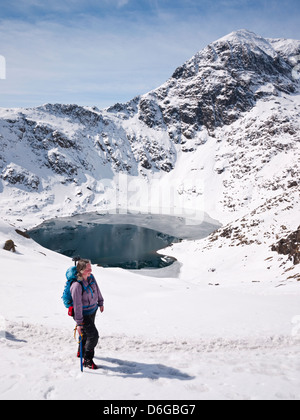 Snowdon unter winterlichen Bedingungen - eine weibliche Hügel Walker auf der Pyg verfolgen mit Blick auf die Gipfel, Yr Wyddfa über Glaslyn Stockfoto