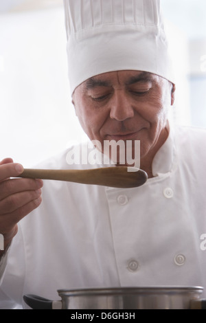 Hispanische Koch schmeckendes Essen in Küche Stockfoto