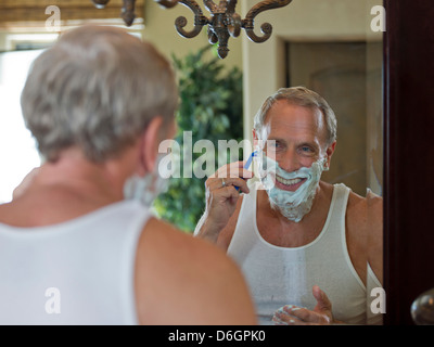 Älterer Mann rasiert sein Gesicht im Badezimmer Stockfoto
