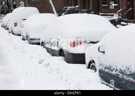 Verschneite Autos auf Stadtstraße Stockfoto