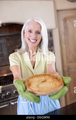 Ältere Frau mit Kuchen in Küche Stockfoto