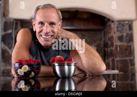 Älterer Mann mit Obst in Küche Stockfoto