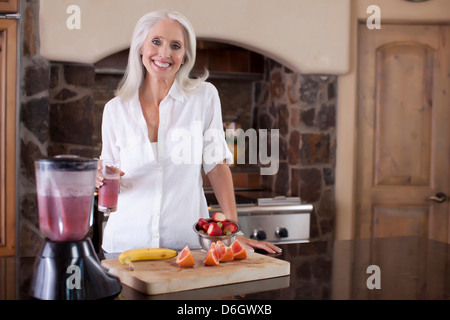 Ältere Frau machen Smoothie in Küche Stockfoto