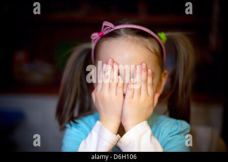Eine fünf-jähriges Mädchen sitzt am Tisch der elterlichen Hause und verbirgt ihr Gesicht in Sieversdorf, Deutschland, 6. Februar 2012. Foto: Patrick Pleul Stockfoto