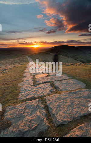 Gepflasterte Fußweg auf Mam Tor mit unscharfen Abbildung zu Fuß, wenn die Sonne in den Peak District Derbyshire England untergeht Stockfoto