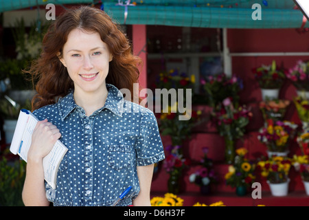 Blumengeschäft Holding Notizblock im shop Stockfoto