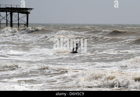 Ein Kitesurfer macht das Beste aus den starken Winden und dem sonnigen Wetter heute, während er am West Pier Brighton UK auf den Wellen reitet Stockfoto