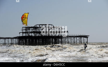 Eine Kitesurfer macht das Beste aus den starken Winden und sonnigem Wetter heute, wie er die Wellen von der West Pier in Brighton reitet. Stockfoto