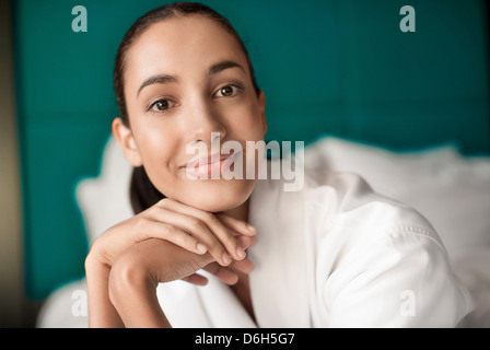 Frau im Bademantel lächelnd auf Bett Stockfoto