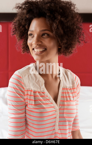 Lächelnde Frau sitzt auf Bett Stockfoto