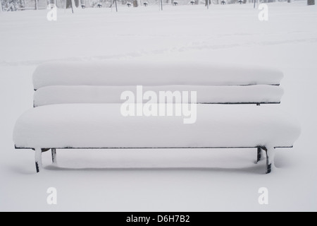 Schnee bedeckte Bank im park Stockfoto