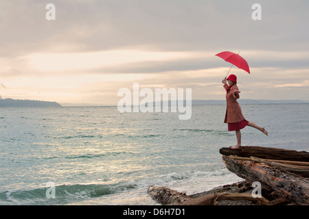 Frau mit Regenschirm auf küstennahen Klippen Stockfoto