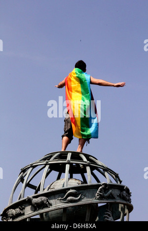 Paris-gay-Pride. Mann eingewickelt in Regenbogenfahne steht auf dem Gipfel der Welt-Statue in den Jardin du Luxembourg, Paris, Frankreich Stockfoto