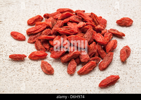 ein Haufen von tibetischen Gojibeeren auf einem groben weißen gemalten Scheune Holz Stockfoto