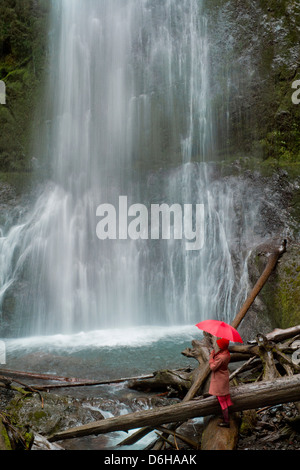 Frau mit Regenschirm Wasserfall zu bewundern Stockfoto