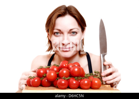 Eine junge Frau mit Messer und roten Strauchtomaten Stockfoto