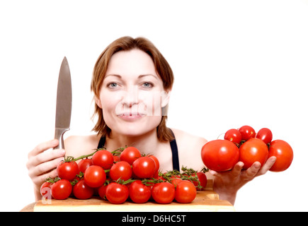 Junge Frau mit Messer und roten Strauchtomaten Stockfoto