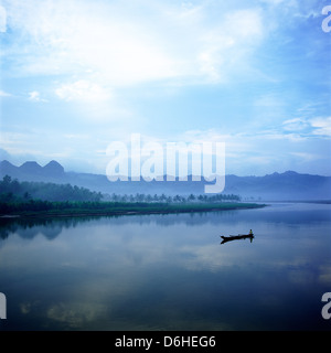 Mann im Boot auf einem nebligen Dämmerung auf dem Bodo-Ijo-Fluss in der Nähe von Ayah, Süd Küste von Java, Indonesien Stockfoto