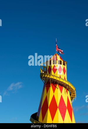 Rote und gelbe Helter Skelter Kirmes Jahrmarktsattraktion mit einem Union Jack gesetzt vor dem blauen Himmelshintergrund Stockfoto