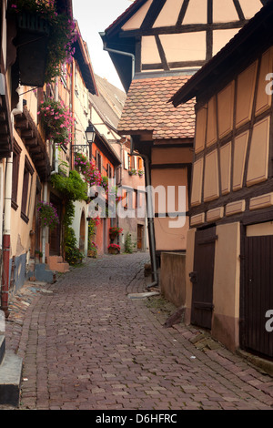 Schiefen Häusern in einer Straße mit mittelalterlichen Fachwerkhäusern in Eguisheim Dorf entlang der berühmten Weinstraße im Elsass/Frankreich Stockfoto