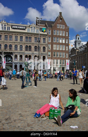 Holland, Amsterdam. Zwei Frauen sitzen auf den gepflasterten Boden, ruhen, reden in Damplatz in Amsterdam Holland. Stockfoto