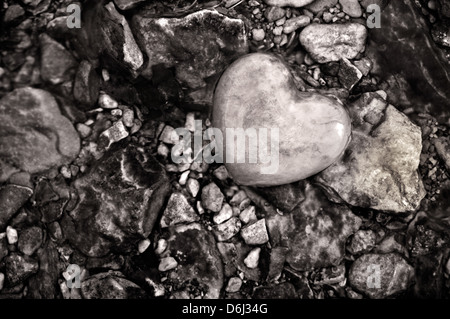 Schwarz / weiß steinerne Herz inmitten Kieselsteine in einem Stream Stockfoto
