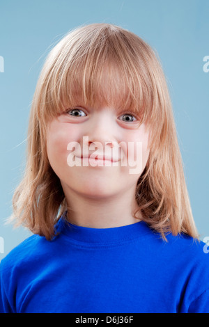 Studio-Porträt eines jungen mit langen blonden Haaren - isoliert auf blau Stockfoto
