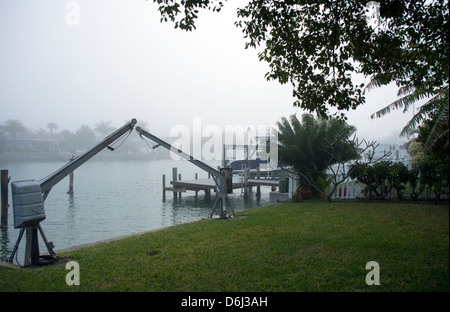 Davit Boot Krane montiert neben Kanal im Nebel in Florida in der Nähe von Palme bei Sonnenaufgang Stockfoto