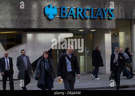 Fußgänger laufen während der hektischen Hauptverkehrszeit am Morgen an einer Filiale der Barclays Bank im Zentrum von London vorbei und halten das rasante urbane Leben im Finanzviertel der Stadt fest. Stockfoto