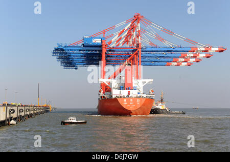 Ein Frachtschiff mit riesigen Containerbrücken beladen kommt an der Pier des JadeWeserPort in Wilhelmshaven, Deutschland, 6. März 2012. Vier neue neue Portalkräne haben endlich nach dem Versand für zwei Monate an Bord die 245 Meter lange "Zhenhua 23' aus China. Die Krane sind für den Eurogate Container Terminal, dem neuen Tiefwasser-Hafen bestimmt. Die Krane markieren die erste arriva Stockfoto