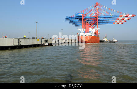 Ein Frachtschiff mit riesigen Containerbrücken beladen kommt an der Pier des JadeWeserPort in Wilhelmshaven, Deutschland, 6. März 2012. Vier neue neue Portalkräne haben endlich nach dem Versand für zwei Monate an Bord die 245 Meter lange "Zhenhua 23' aus China. Die Krane sind für den Eurogate Container Terminal, dem neuen Tiefwasser-Hafen bestimmt. Die Krane markieren die erste arriva Stockfoto