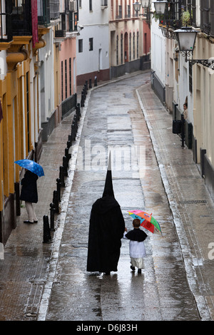 Büßer während der Semana Santa (Karwoche) entlang verregnete Straße, Sevilla, Andalusien, Spanien, Europa Stockfoto